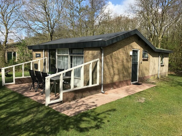 A small brick building with a covered patio area, a white railing, and a table with chairs. - Secluded Holiday Home in Ballum Frisian Islands (Ballum-Ameland)