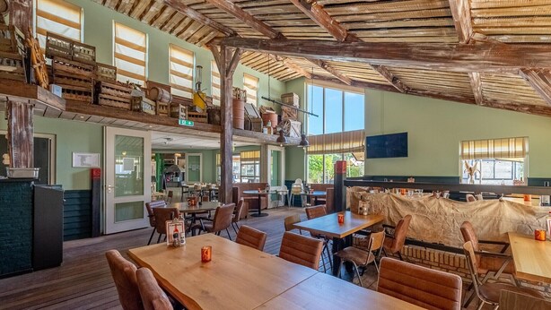 A rustic restaurant with wooden tables and chairs, a mezzanine level with wooden crates, and large windows allowing natural light. - Villa with Pet Access (Hollum)
