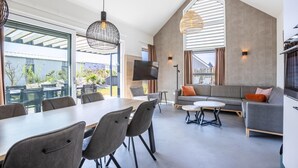 A spacious living area with a dining table, sofas, and a TV. - Villa with Pet Access (Hollum)