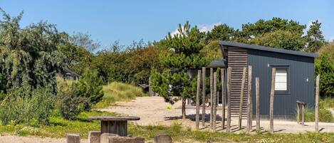 Eine rustikale Holzhütte mit Metalldach, umgeben von dichter Vegetation und blauem Himmel.