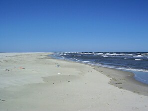 A beach with a wide sandy shore and ocean waves.
