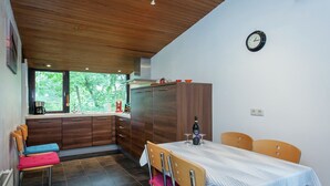 Een moderne keuken met houten kastjes, een eettafel met stoelen en een klok aan de muur.