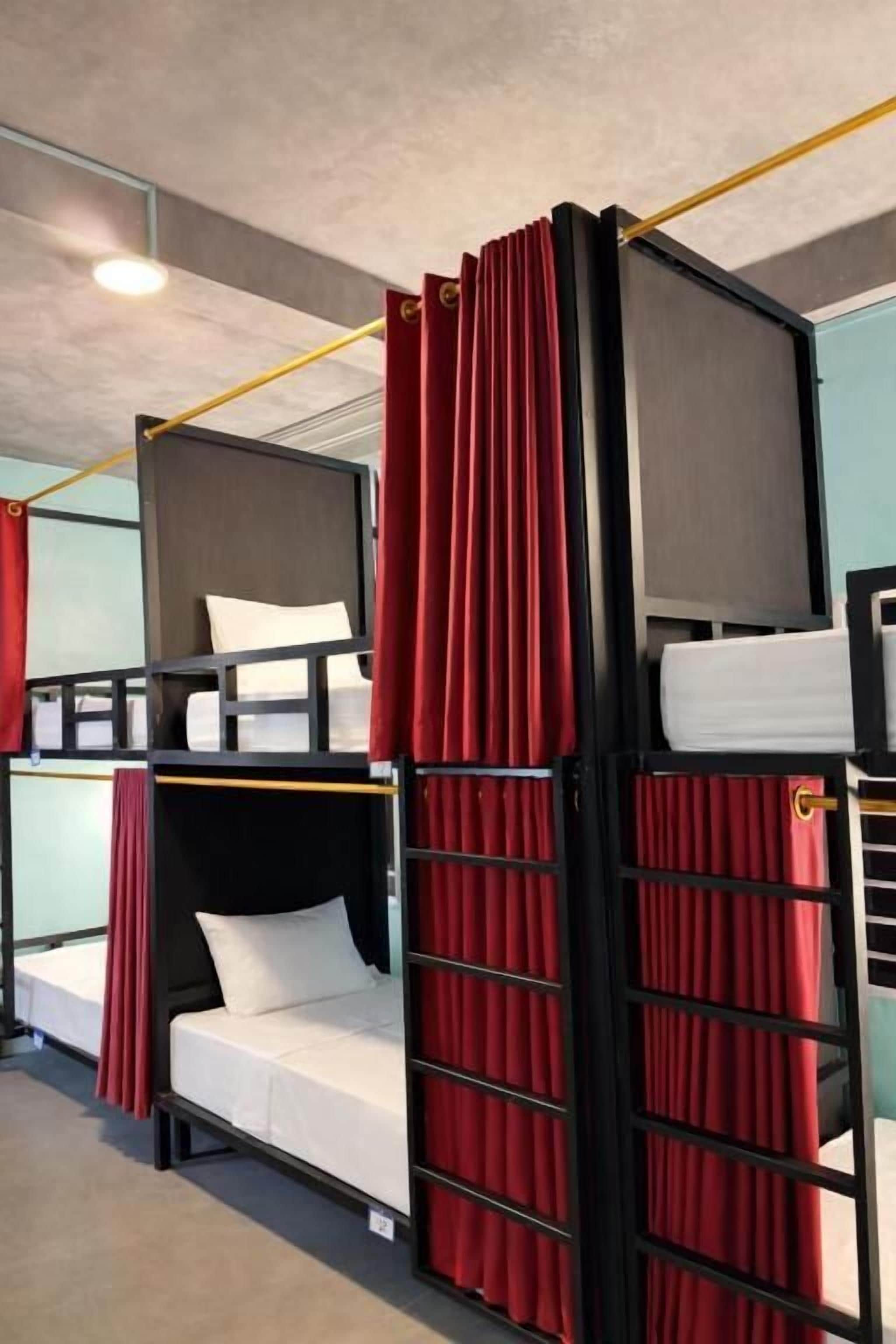 A bunk bed room with red curtains, a white mattress, and a grey headboard.