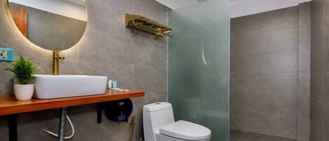 Ein modernes Badezimmer mit einem weißen Waschbecken, einem goldenen Wasserhahn und einer Duschkabine aus Glas.