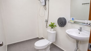 A bathroom with a toilet, a sink, a shower, and a toilet paper holder. - Bliss & Beats Hostel (Phnom Penh)