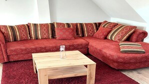 A red sectional sofa with patterned cushions, a wooden coffee table, and a red carpet. - Ferienwohnung im idyllischen Ziesar (Ziesar)