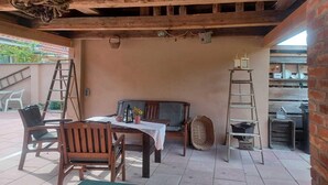 A rustic outdoor patio with wooden furniture, a table with a white tablecloth, and a bench. - Ferienwohnung im idyllischen Ziesar (Ziesar)