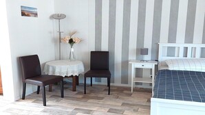 A bedroom with a bed, two chairs, a small table with a lamp, and a vase with flowers. - Ferienwohnung im idyllischen Ziesar (Ziesar)