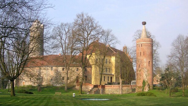 A historic building with a tower, surrounded by trees and a grassy area. - Ferienwohnung im idyllischen Ziesar (Ziesar)