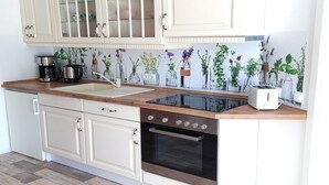 A kitchen with white cabinets, a stainless steel oven, a black stovetop, and a wooden countertop. - Ferienwohnung im idyllischen Ziesar (Ziesar)