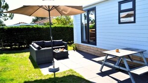 Eine Terrasse mit einer Couch, einem Sonnenschirm und einem Tisch.