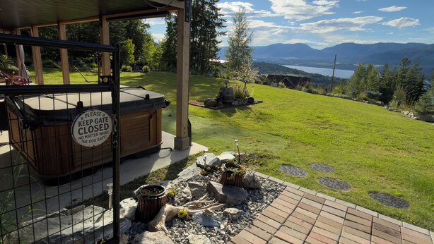 Une terrasse avec un jacuzzi, une plateforme en bois et une vue sur un lac et des montagnes.
