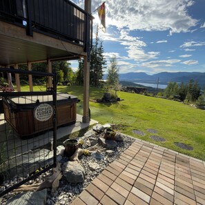 Une terrasse avec un jacuzzi, une plateforme en bois et une vue sur un lac et des montagnes.