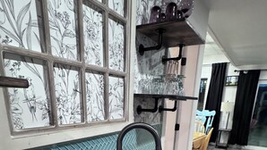 Une cuisine avec un plan de travail en bois, un évier noir et une fenêtre ornée d’un papier peint à motifs floraux.