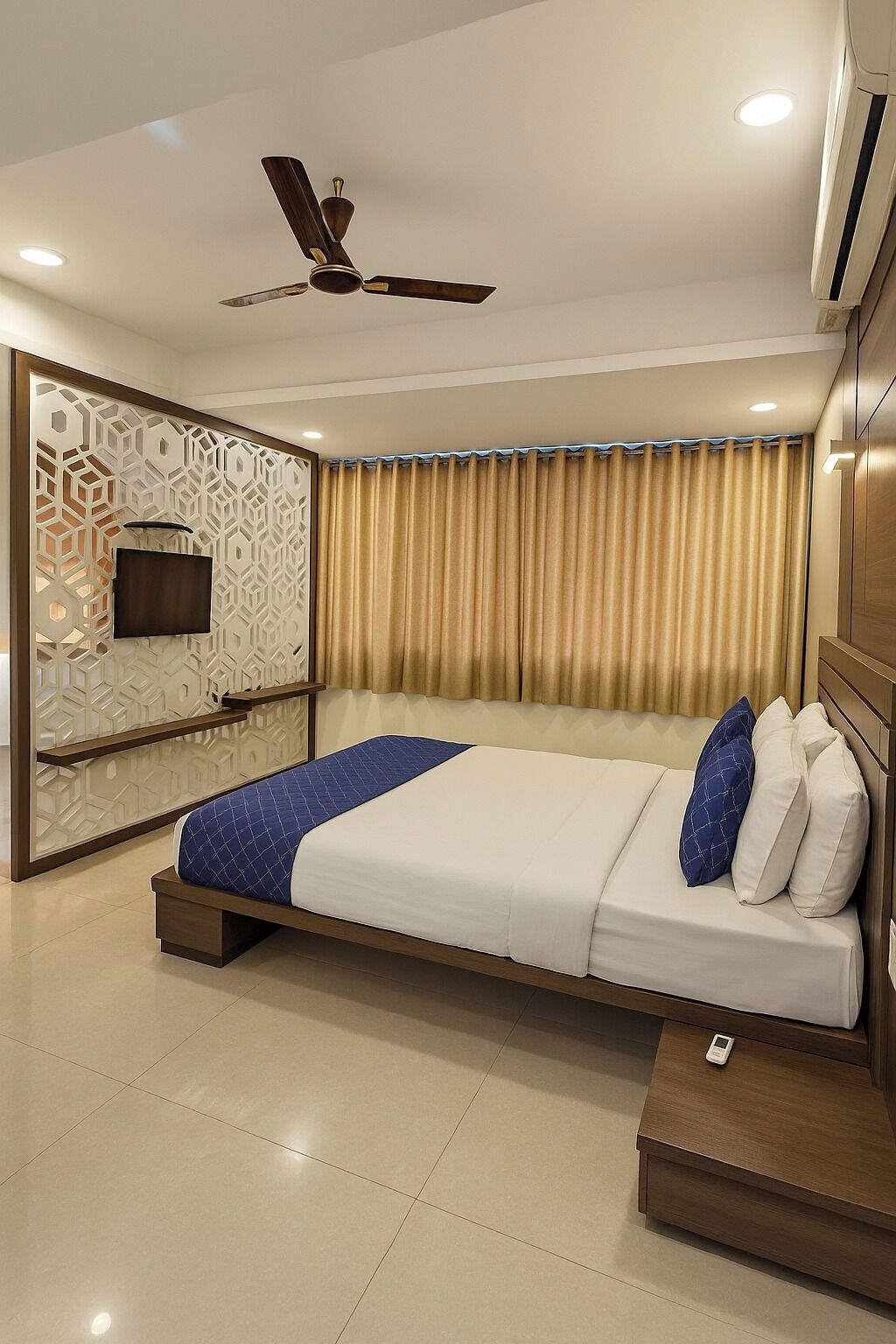A modern hotel room with a large bed, a ceiling fan, a TV mounted on a decorative wall, and a window with curtains.