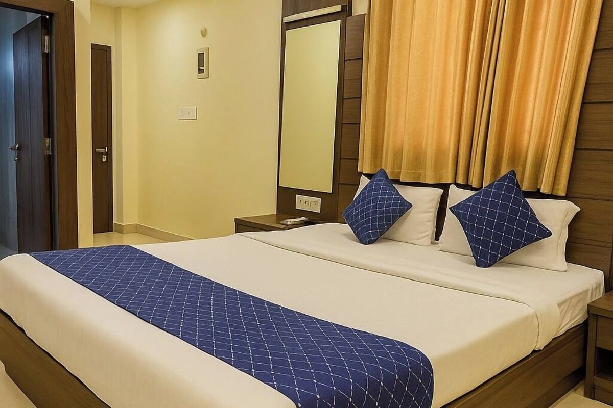 Ein Hotelzimmer mit einem großen Bett, einem Holzkopfende, beige gefärbten Wänden und einem Deckenventilator.
