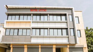 Un moderno edificio de hotel con un letrero destacado que dice "HOTEL ATTHI". Tiene varios pisos con ventanas amplias y un techo plano.