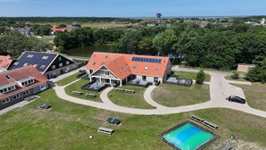 A residential area with a large house featuring a swimming pool, solar panels, and a well-maintained lawn.