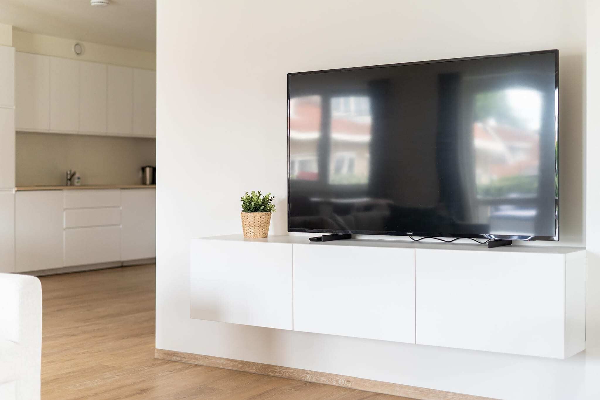 Un salon moderne avec un téléviseur à écran plat fixé sur un meuble blanc.