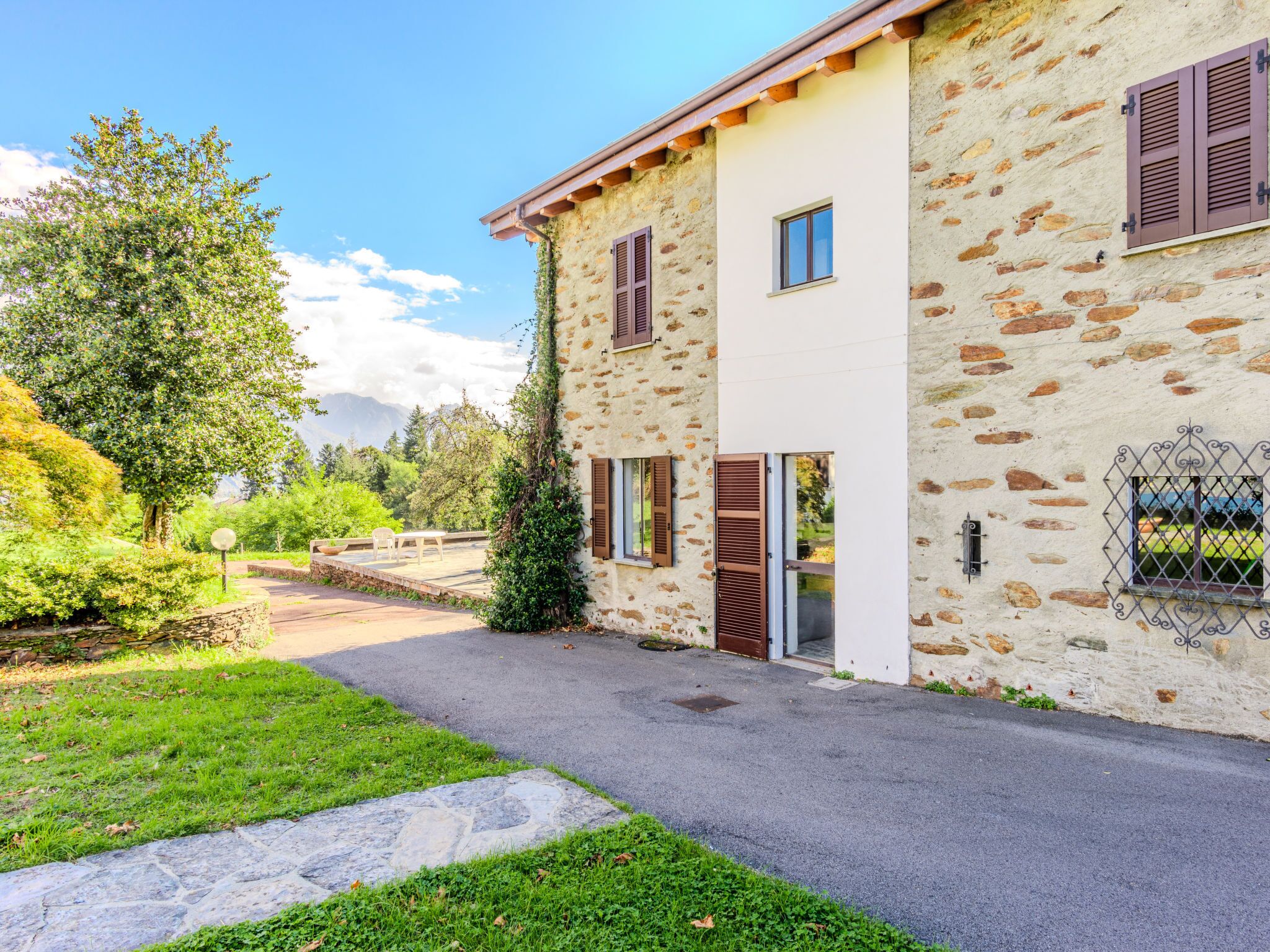 Un bâtiment en pierre avec une allée pavée et un petit jardin.