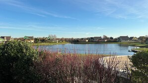 Una vista tranquila de un lago con un muelle, casas y cielo despejado.