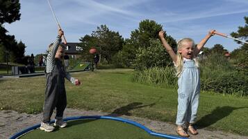 Deux enfants jouent au minigolf en plein air.
