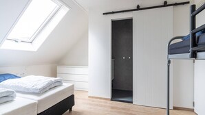 A bedroom with a bunk bed, a skylight, a sliding door closet, and a wooden floor. - Group Apartment Ameland near Nes (Nes)