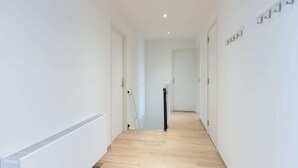 A hallway with white walls, wooden flooring, and a radiator on the left. - Group Apartment Ameland near Nes (Nes)