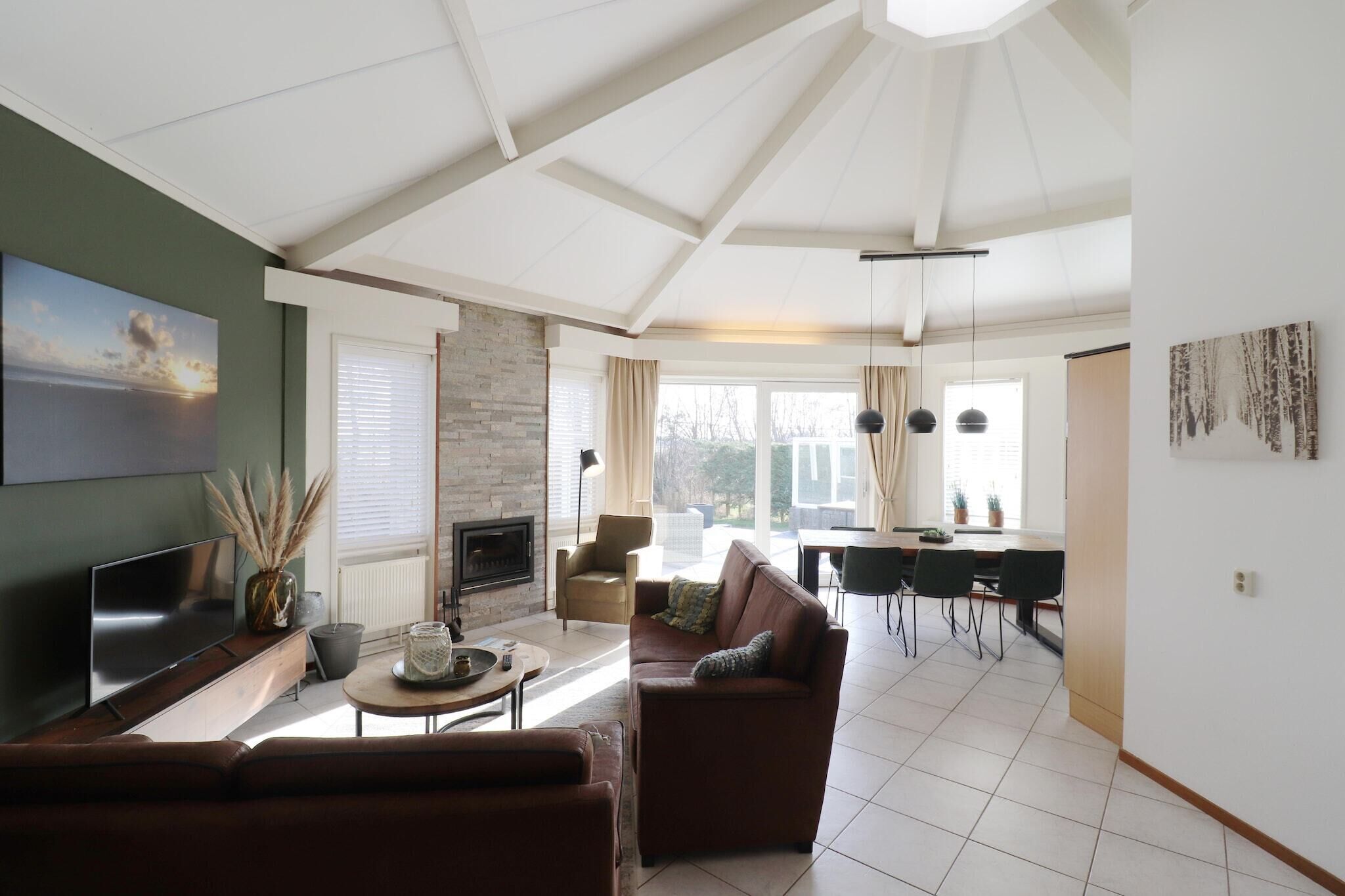 A modern living room with a sofa, TV, fireplace, and dining area with chairs and a table.