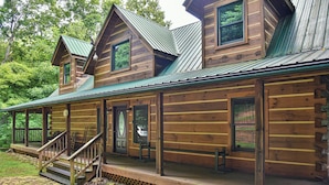 A log cabin with a porch, a staircase, and a metal roof. - Bair Necessities relaxing Cabin (Old Fort)