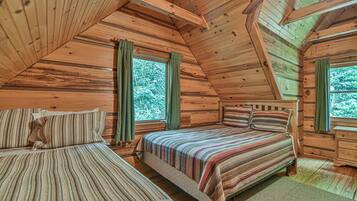 A cabin with two wooden beds, a wooden ceiling, and large windows with curtains.