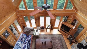 A cozy cabin interior with a wooden ceiling fan, a sofa, a coffee table, and a stone fireplace. - Bair Necessities relaxing Cabin (Old Fort)
