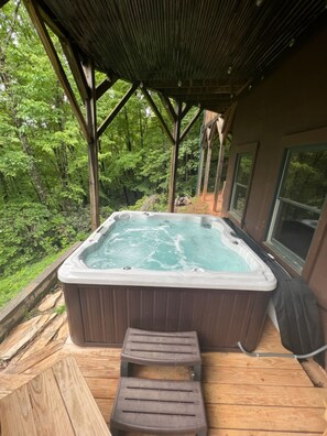 A hot tub on a wooden deck with a view of a forest. - Bair Necessities relaxing Cabin (Old Fort)