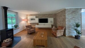 A modern living room with a fireplace, a large flat-screen TV, and two leather sofas. - Spacious Country Retreat (Den Burg)