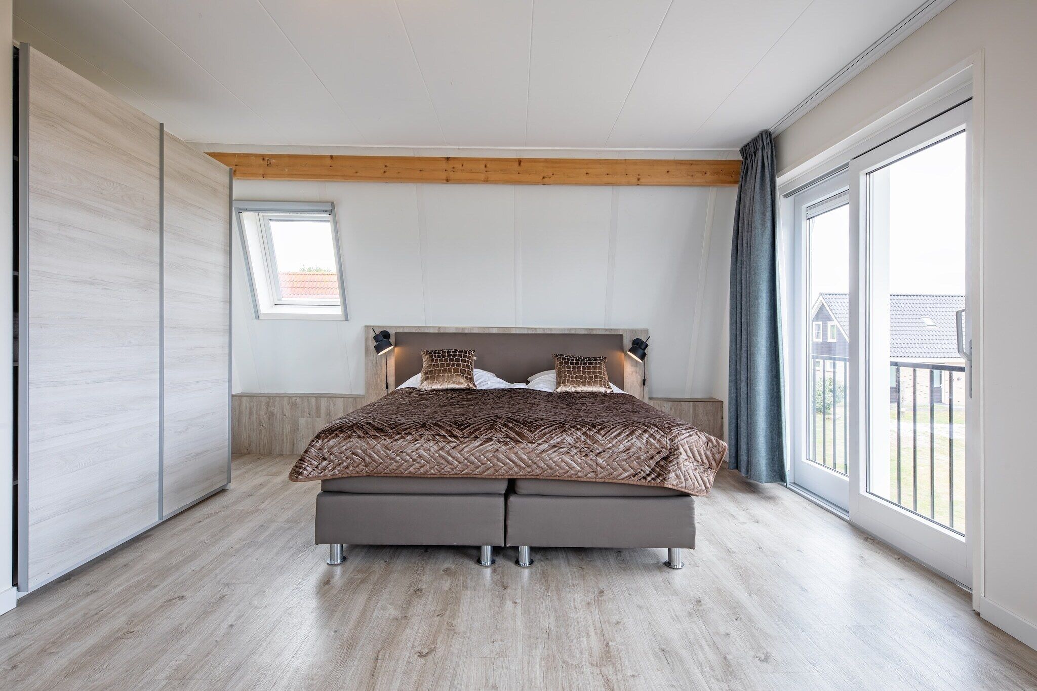 A modern bedroom with a large bed, a window, and a view of the outside.