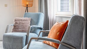 A seating area with two chairs, one with a plush cushion and the other with a patterned cushion.