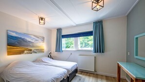 A bedroom with a bed, a bedside table, a window with curtains, a radiator, and a wall-mounted picture. - Cozy holiday home in Den Burg with hot tub (Den Burg)