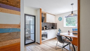 A modern kitchen with wooden flooring, white cabinets, and a dining area with a round table and chairs. - Cozy holiday home in Den Burg with hot tub (Den Burg)