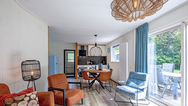 A modern living room with a dining area, a kitchen in the background, and a large sliding glass door to an outdoor patio. - Cozy holiday home in Den Burg with hot tub (Den Burg)