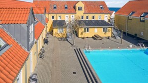 Ein Gebäude mit Schwimmbad, roten Ziegeldächern und einem Innenhof mit Sitzgelegenheiten.