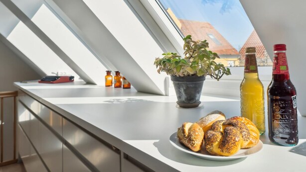 Eine moderne Küche mit Dachfenster, einer Topfpflanze und einer Auswahl an Gebäck.