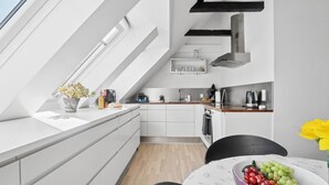 Eine moderne Küche mit Dachfenstern, weißen Schränken und einem Essbereich mit Tisch für zwei Personen.