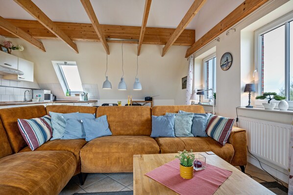 Ein modernes Wohnzimmer mit einer braunen Couch, einem Holztisch und Pendelleuchten.