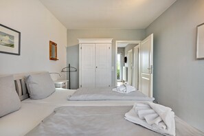 Ein Schlafzimmer mit zwei Betten, einem Kleiderschrank, einem Nachttisch und einem Spiegel.