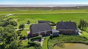 Een groot huis met een pannendak, omgeven door een verzorgd gazon en een kleine vijver.