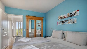 Une chambre avec un grand lit, une armoire en bois et un miroir.