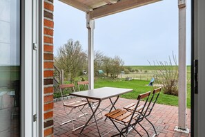 Un patio con mesa y sillas, un muro de ladrillo y vistas al campo.