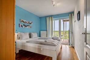 Un dormitorio con cama, un radiador, una ventana con cortinas y vistas al exterior.