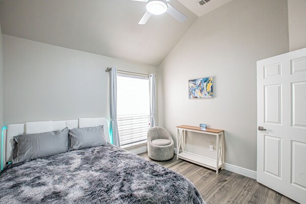 A bedroom with a bed, a chair, a desk, and a door.