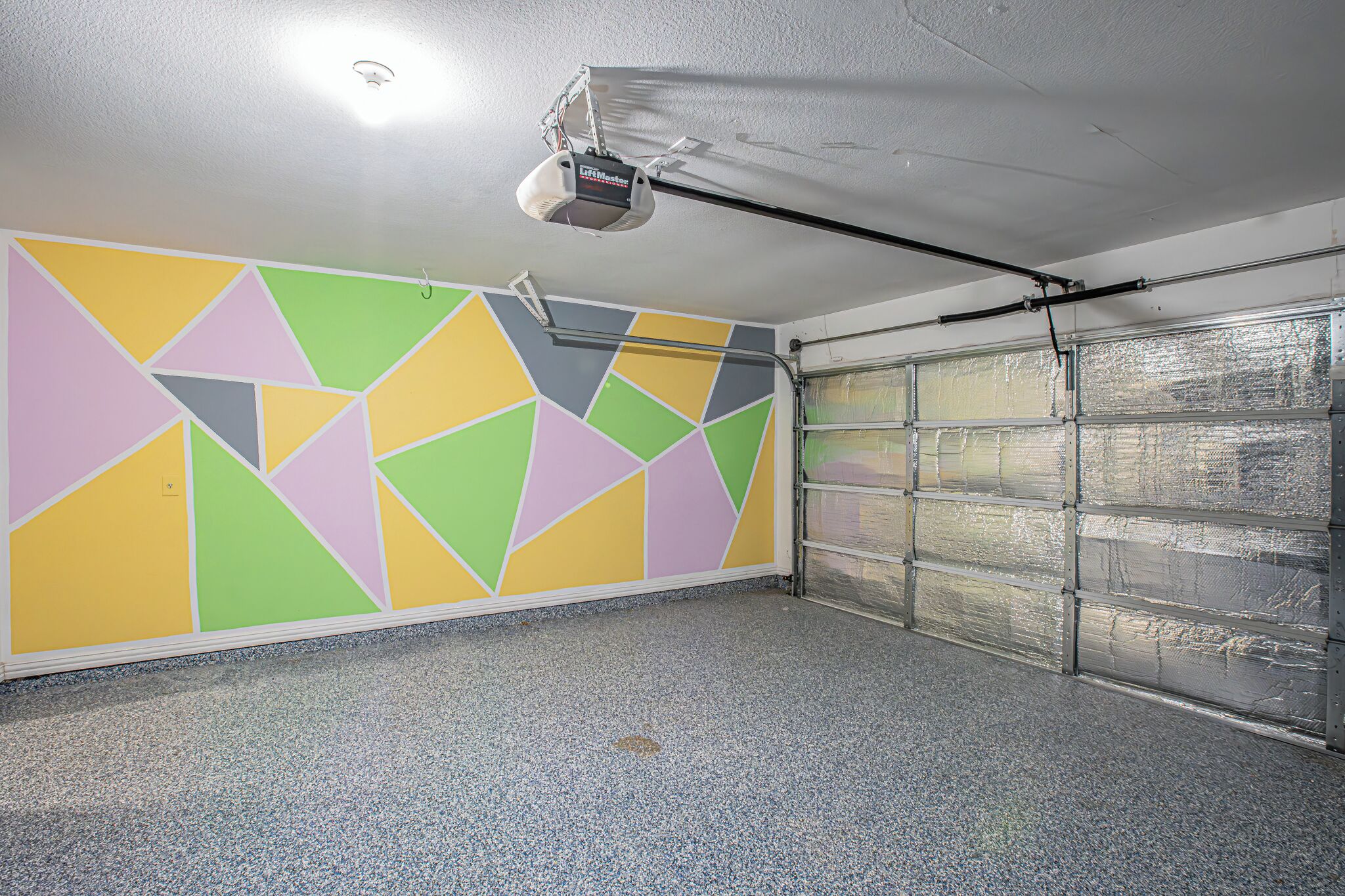 A garage with a colorful geometric wall design and a garage door.